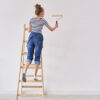 Rear view of woman with paint roller painting wall